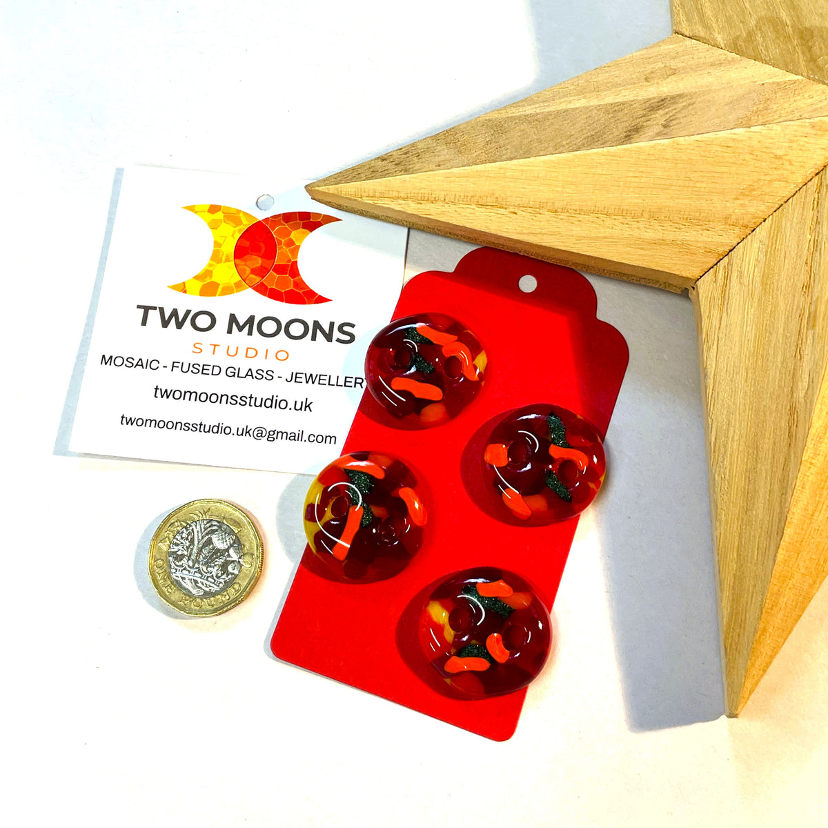 Four red fused glass buttons displayed on a red card
