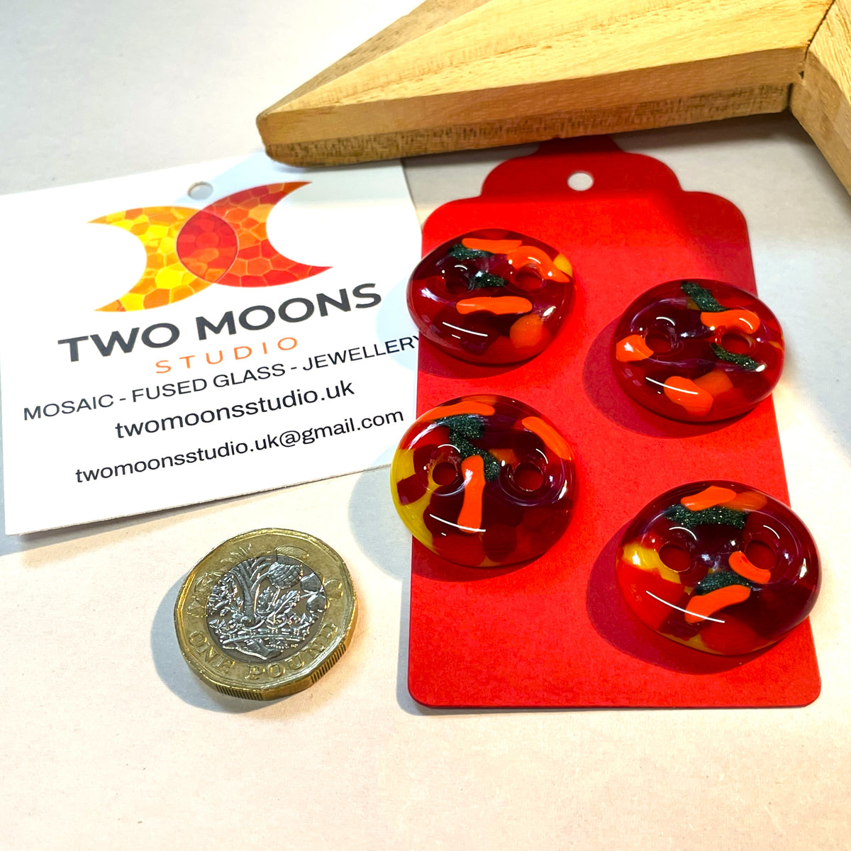 Close-up of four red, orange, yellow and green fused glass buttons