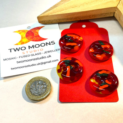 Close-up of four red, orange, yellow and green fused glass buttons