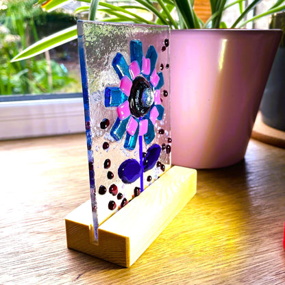 Close view of handmade fused glass flower panel and pine stand