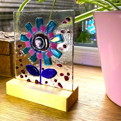 Freestanding turquoise and pink fused glass flower panel in a pine base