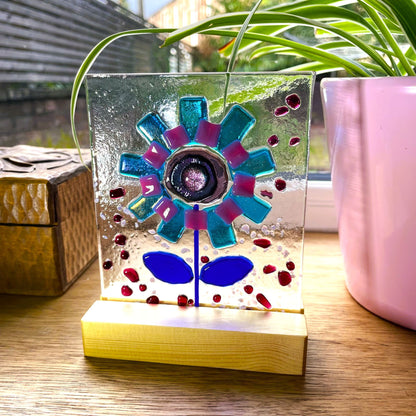 Side view showing the glass flower panel slotted into its pine display base