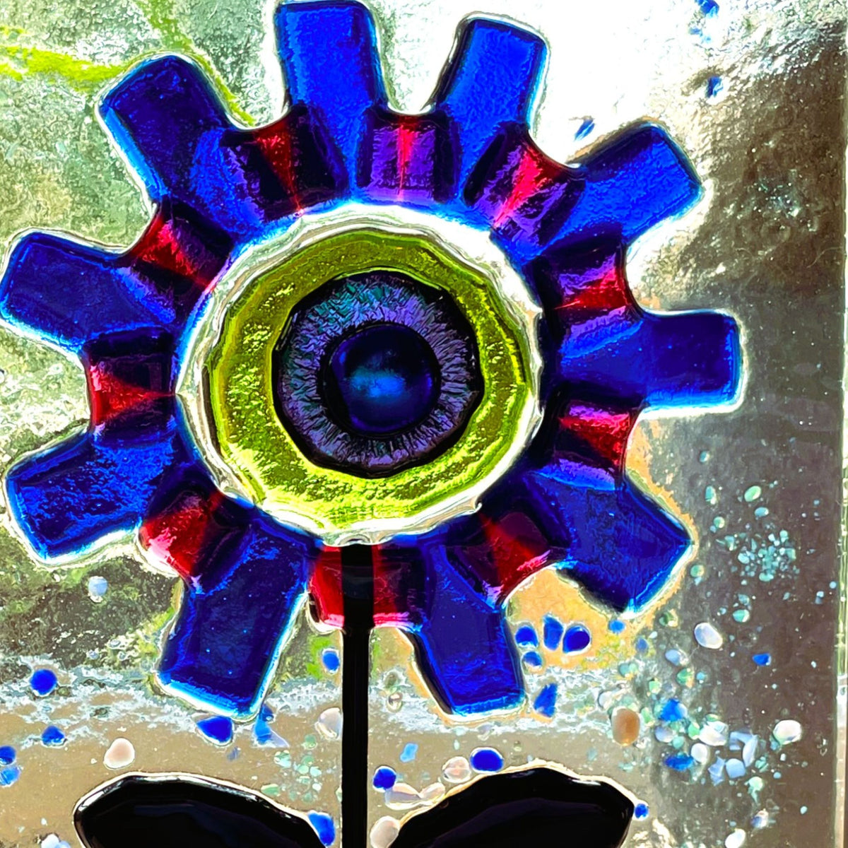 Angled view of freestanding blue and red fused glass flower art