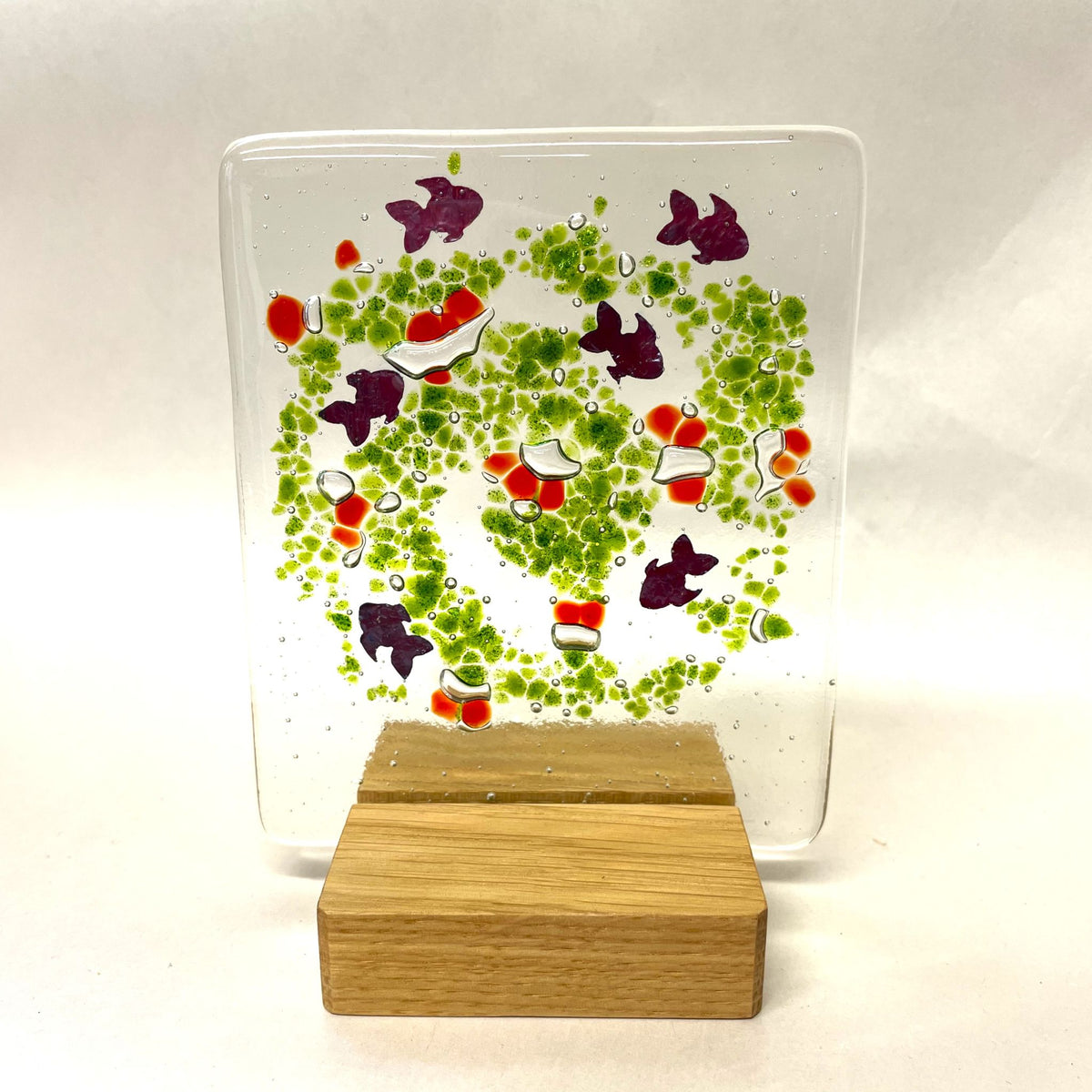 Fused-glass suncatcher with little copper fish and a square wooden base