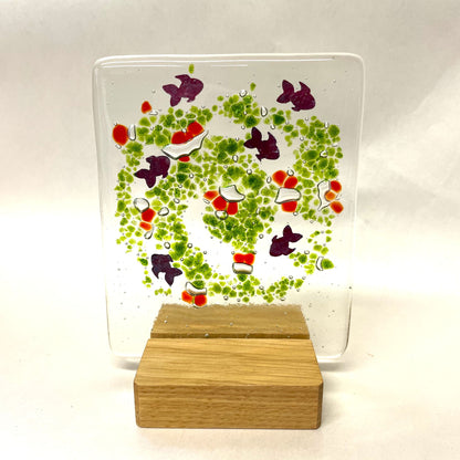 Fused-glass suncatcher with little copper fish and a square wooden base