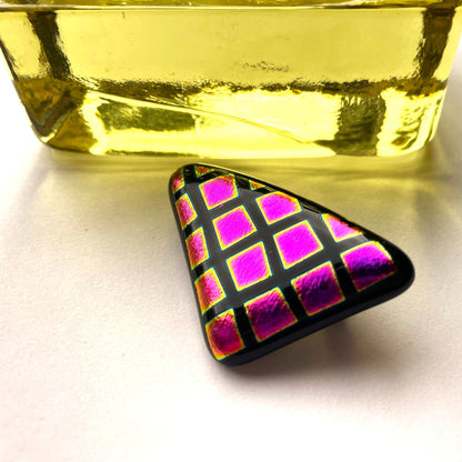 Close view of a bright geometric brooch with pink, gold and purple dichroic glass