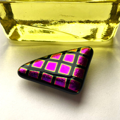 Back of a geometric black fused glass brooch showing the silver-coloured brooch fitting