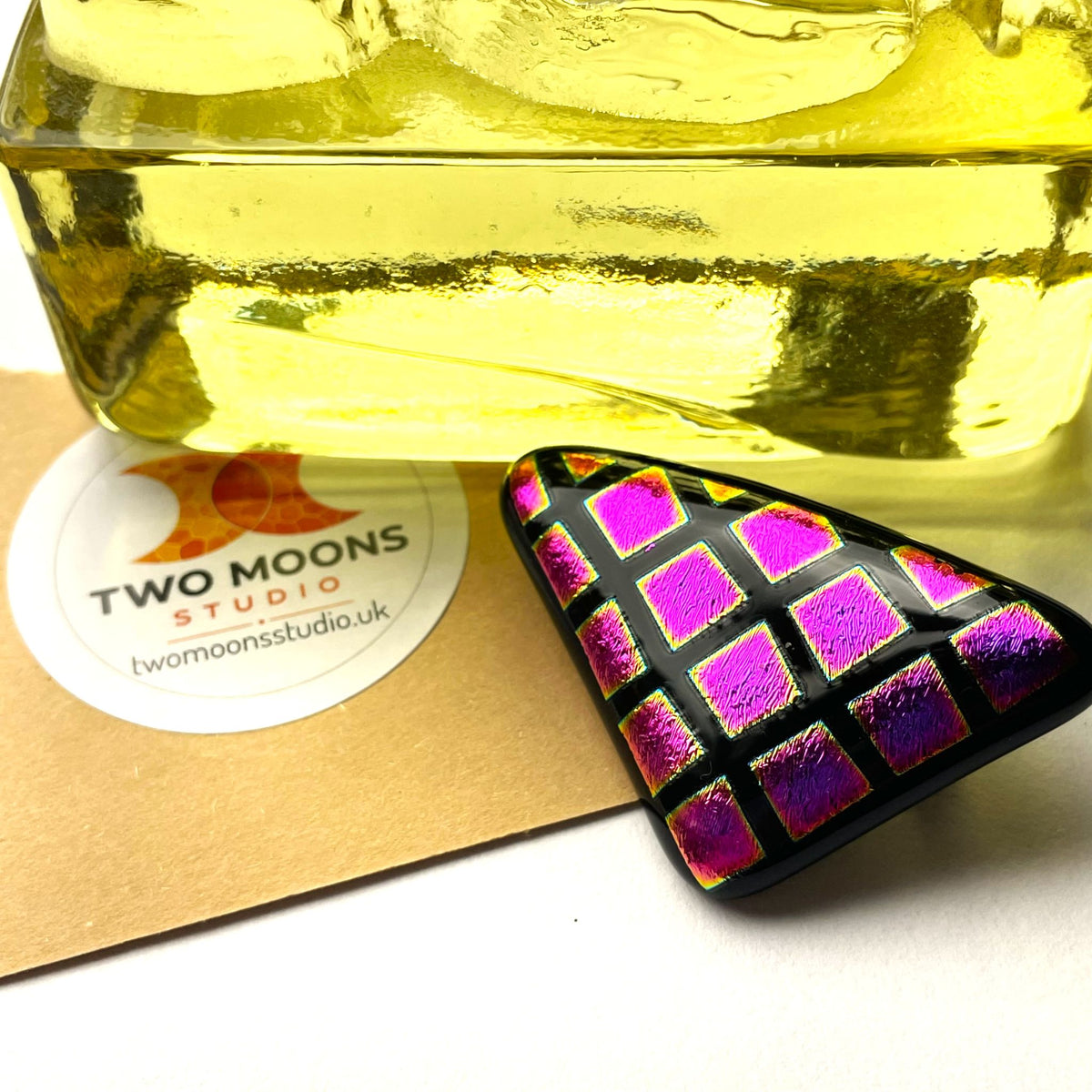 Geometric fused glass brooch with glowing pink and purple dichroic squares on black glass