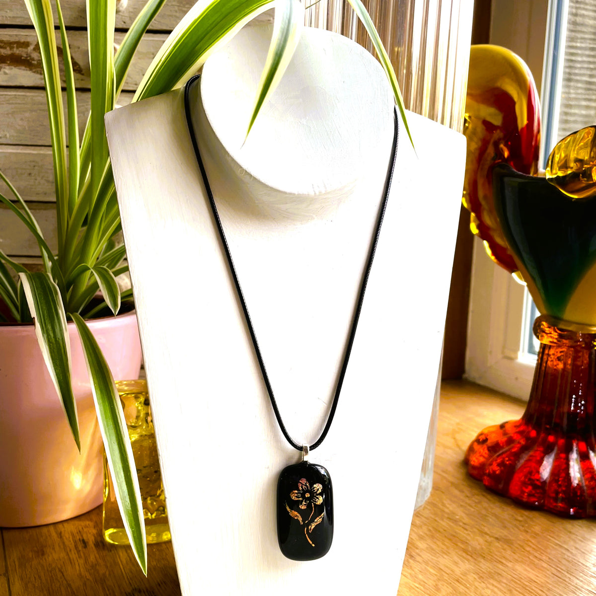 Vintage-inspired rose fused glass pendant with gold and copper detail shown on a black cord necklace