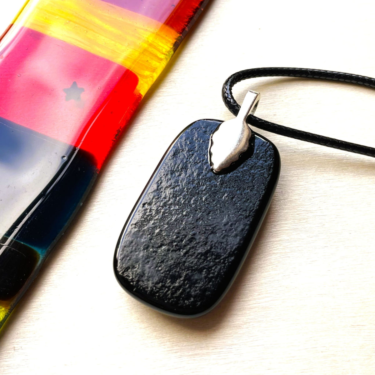 Vintage-inspired fused glass pendant with gold and copper floral dichroic detail on a black cord necklace