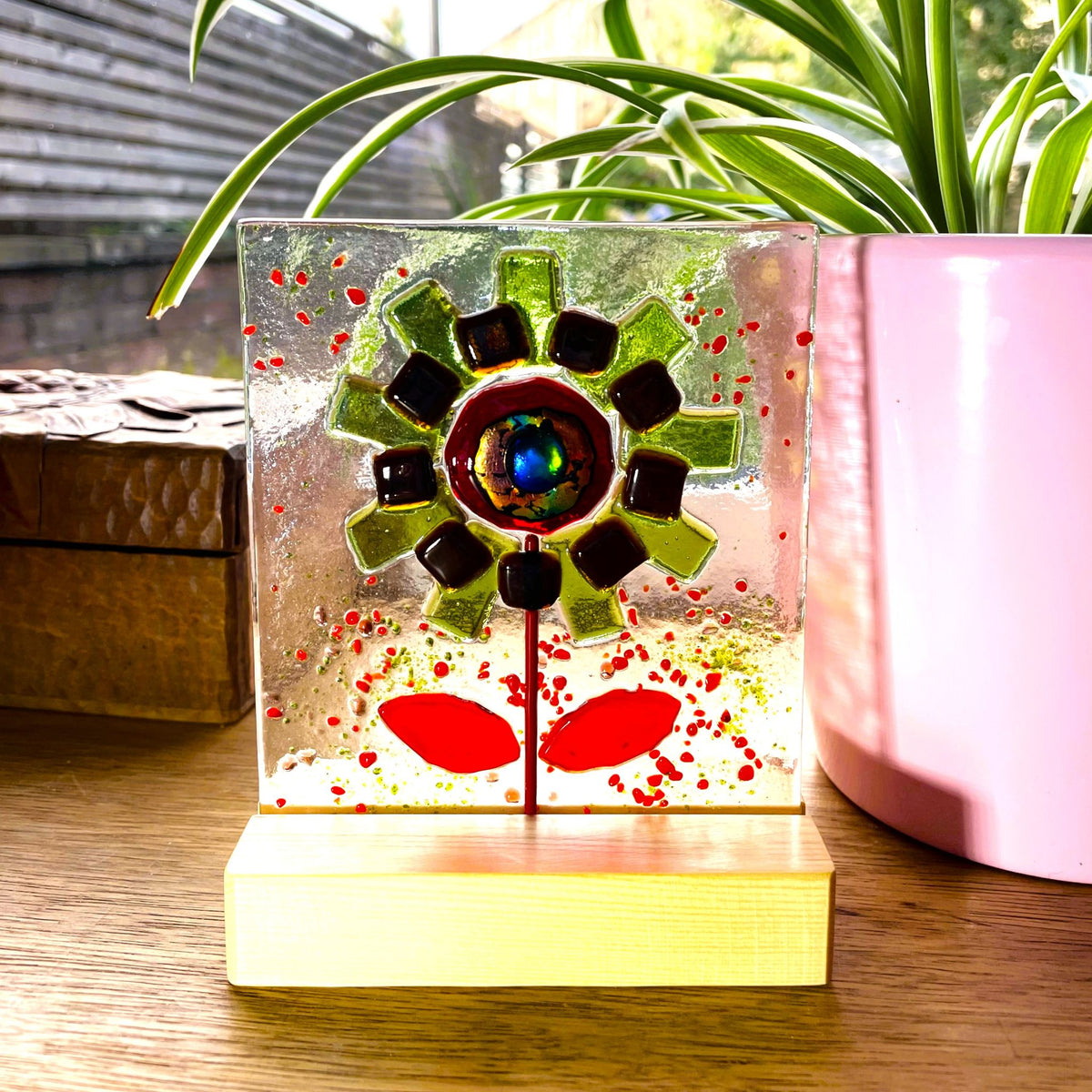 Front view of green fused glass flower with red leaves and pine stand