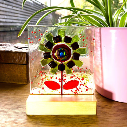 Front view of green fused glass flower with red leaves and pine stand