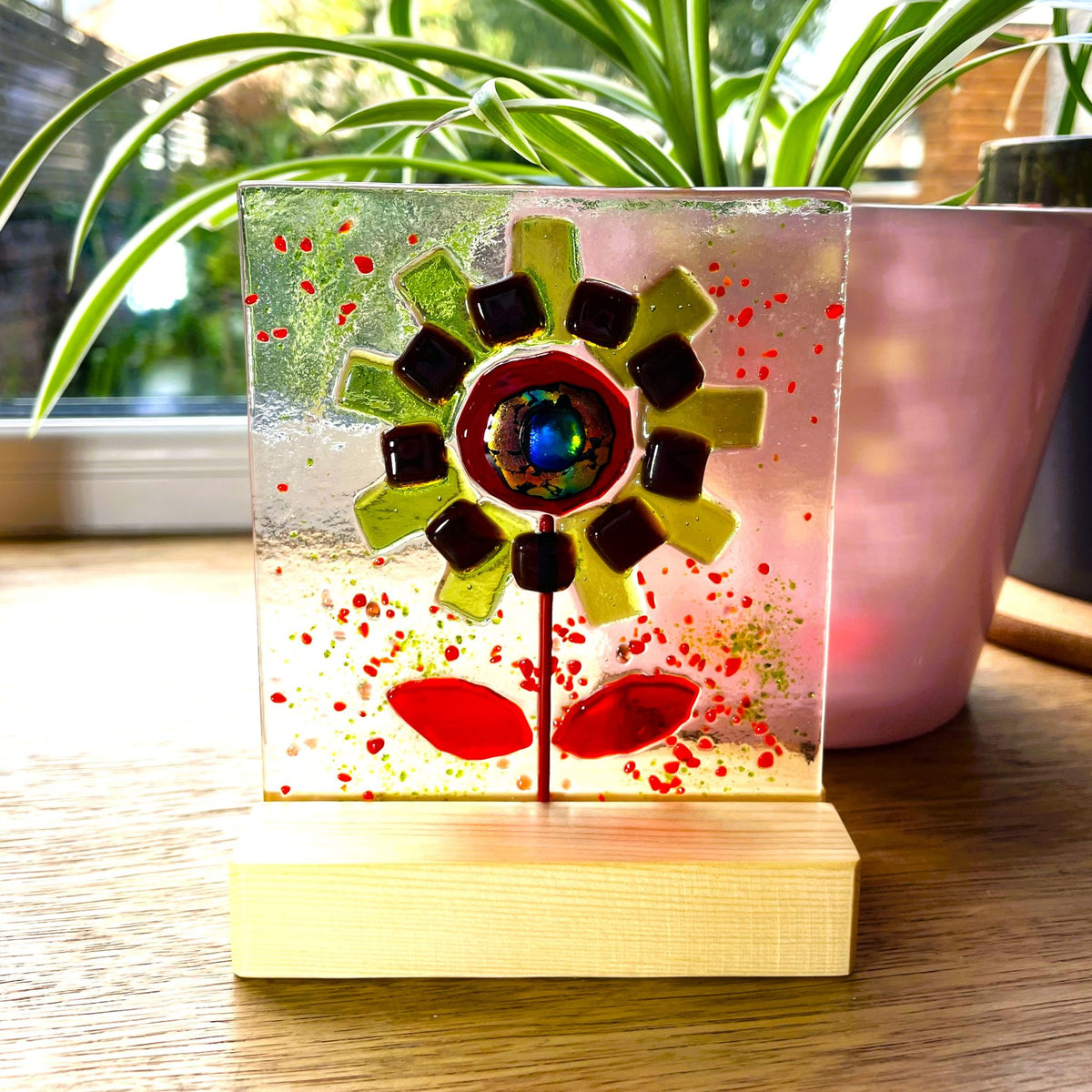 Close-up of the jewel-like iridescent centre in a green and red fused glass flower