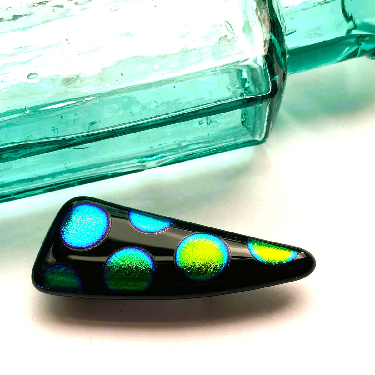 Back of a long black fused glass brooch showing the silver-coloured brooch fitting