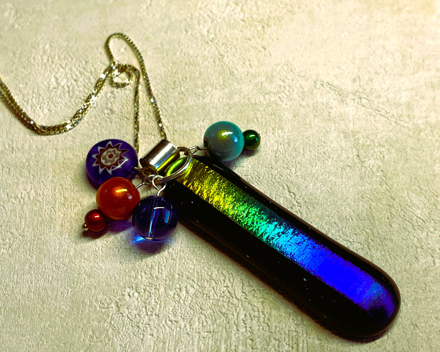 A slice of Rainbow fused glass pendant with added beads