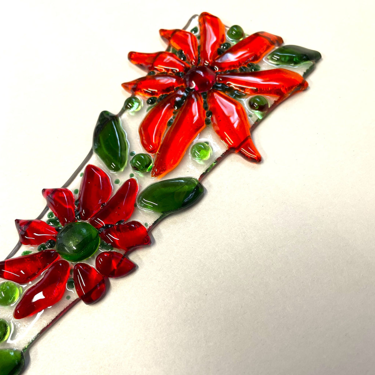 Bright red fused-glass flower plant stake shown outdoors in sunlight