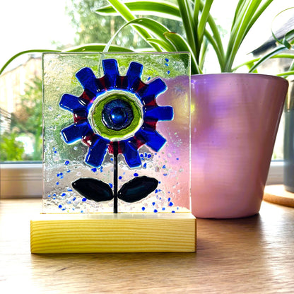 Blue glass flower suncatcher with vivid green centre on a windowsill