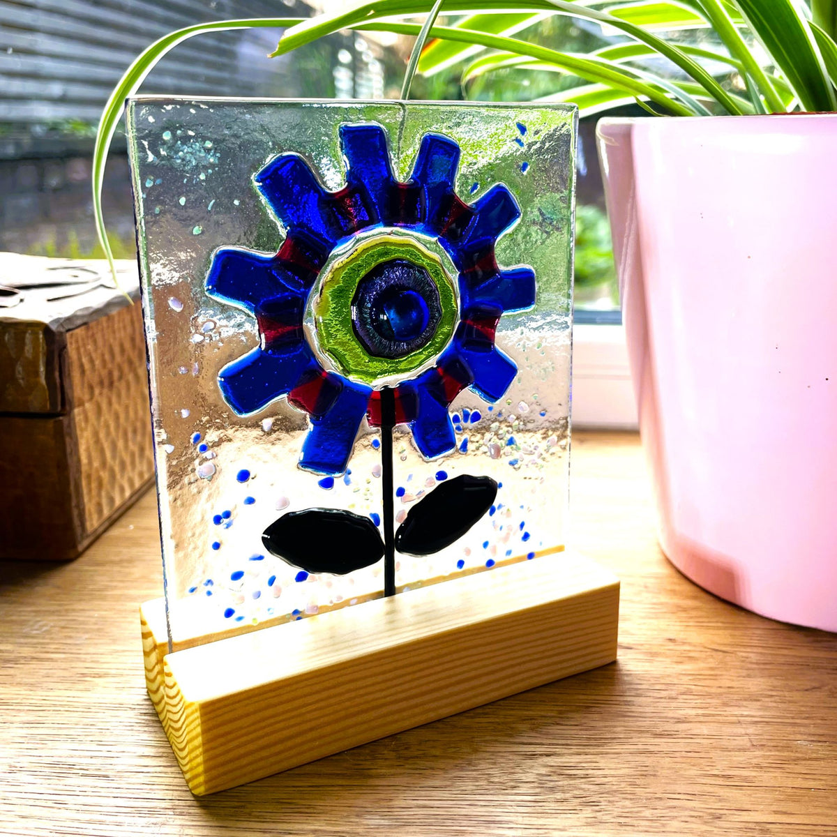 Blue and red fused glass flower suncatcher standing in a natural pine base