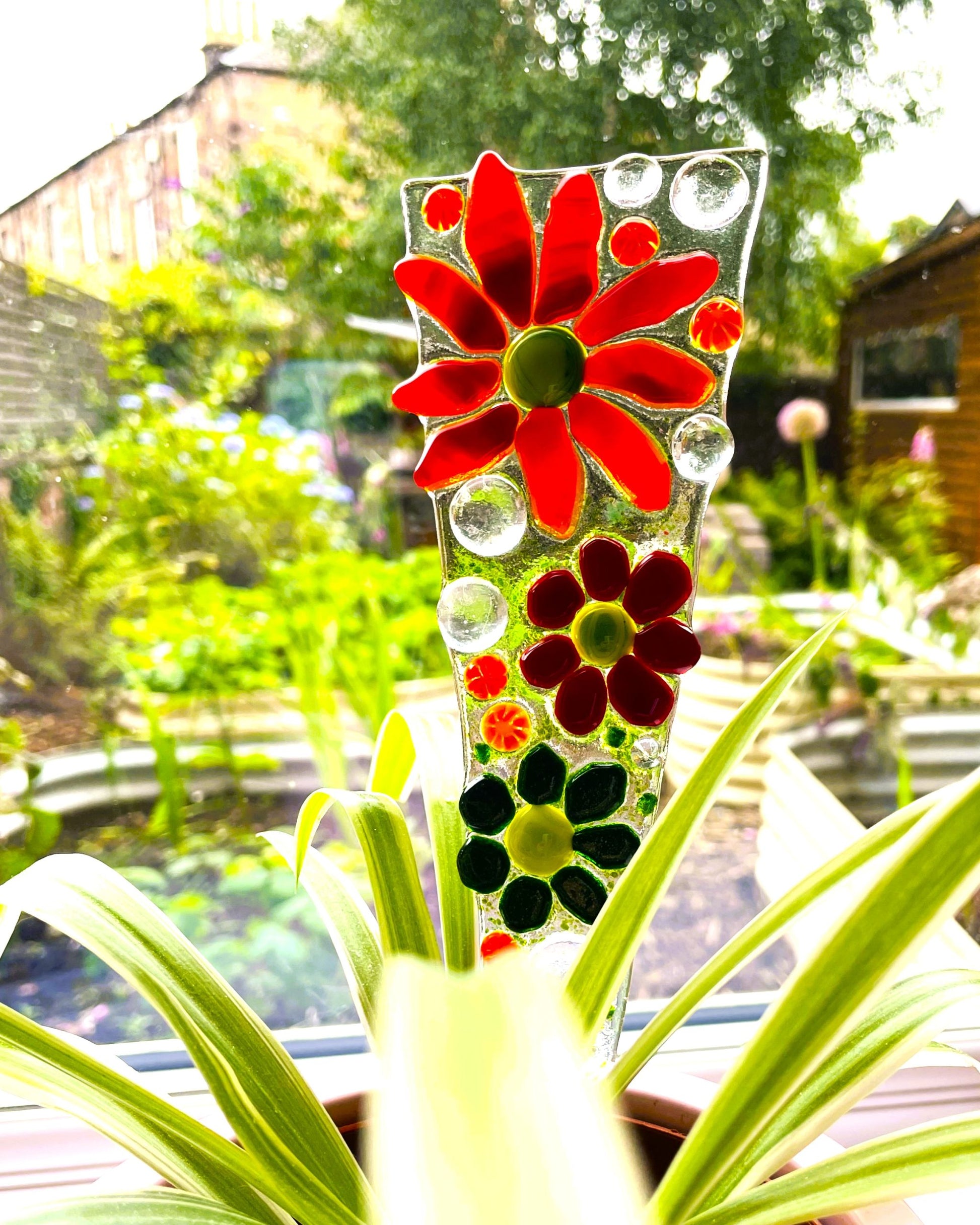 Close up of red fused glass flower plant stake lying flat