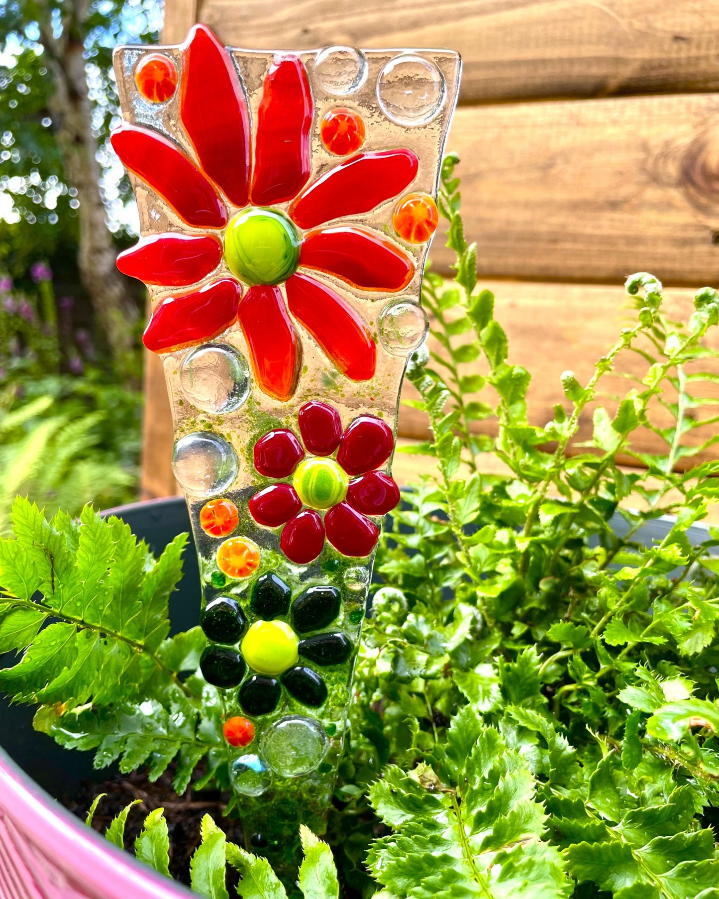 Red fused glass flower plant stake displayed in garden plant pot