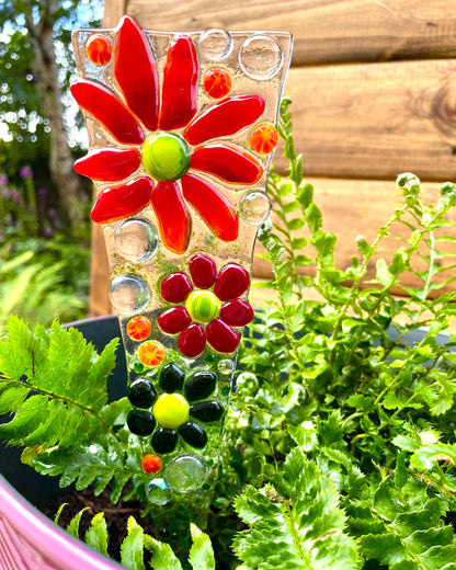 Red fused glass flower plant stake displayed in garden plant pot