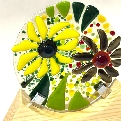 Front view of a colourful summer garden fused-glass roundel in a wooden base