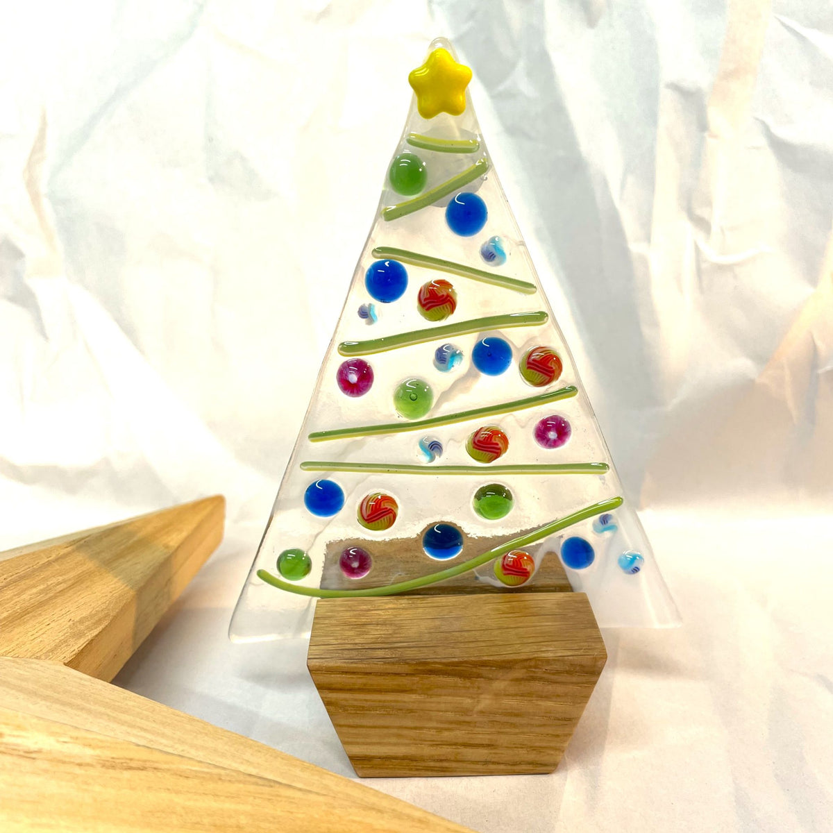 Colourful fused-glass Christmas tree displayed with oak base