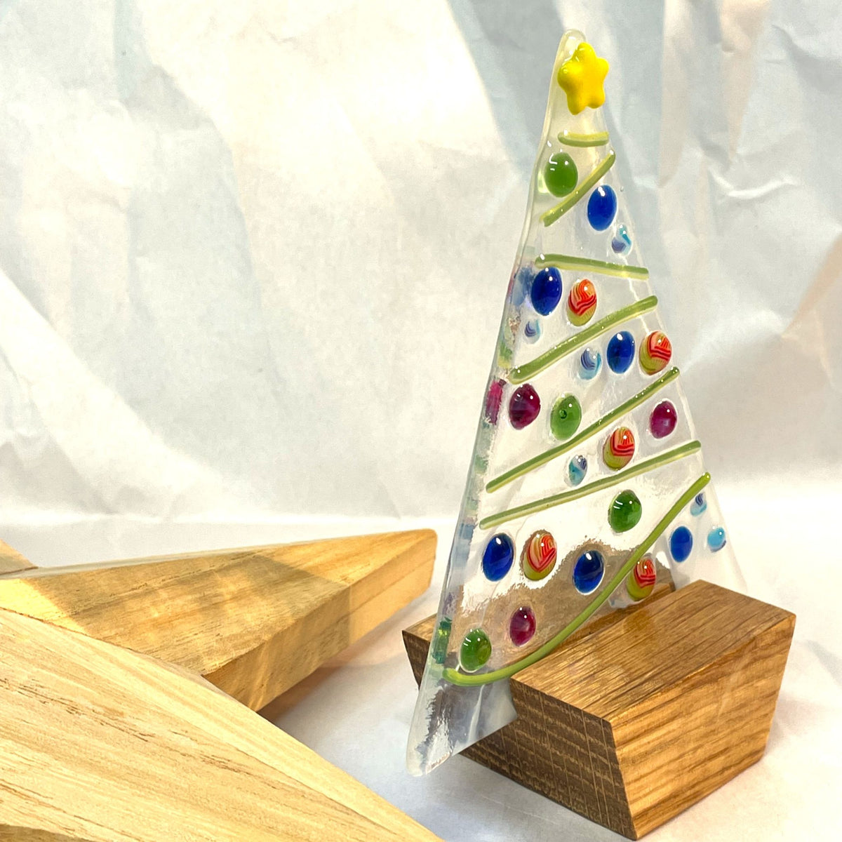 Fused-glass Christmas tree sitting securely in its oak wooden base