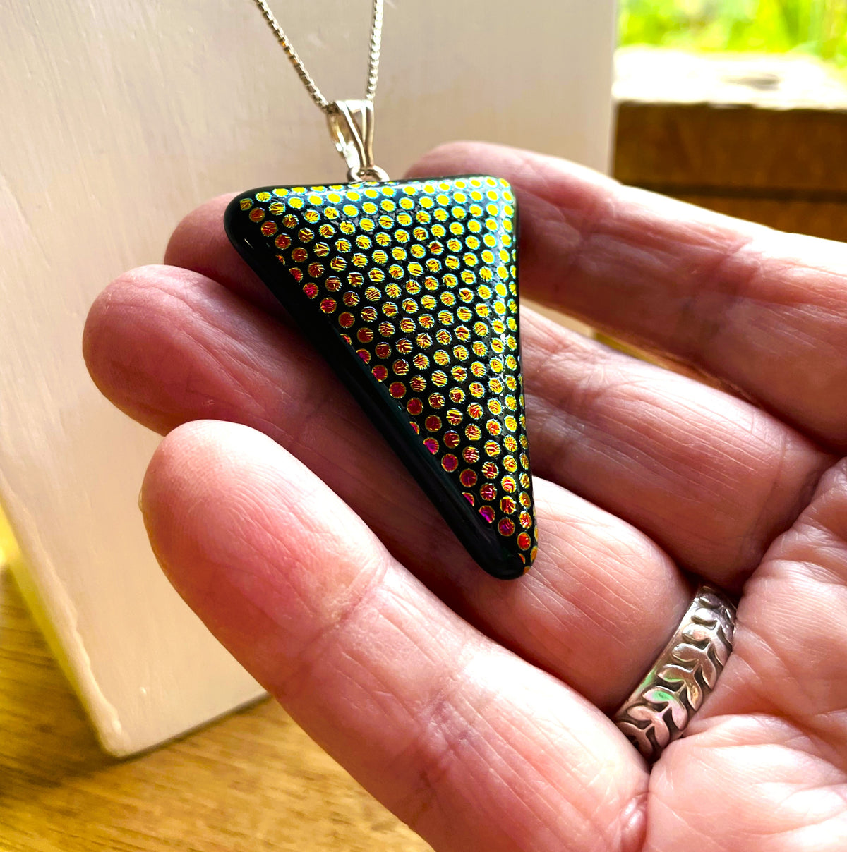 Black fused glass triangle pendant with rows of colourful textured dichroic dots